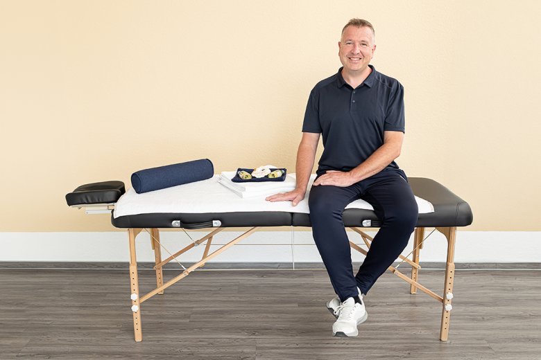 Oliver Müller auf der Massageliege sitzend
